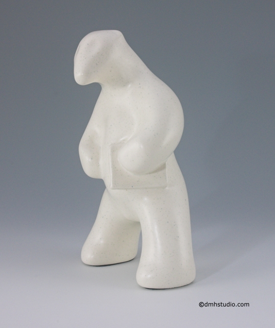 Large image of standing polar bear sculpture with book, in carrara white glaze. Portrait facing to the viewers left.