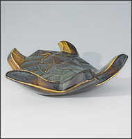 Image of Flying Sea Turtle sculpture in gold and green glaze, seen slightly from above, landed toward the viewer.