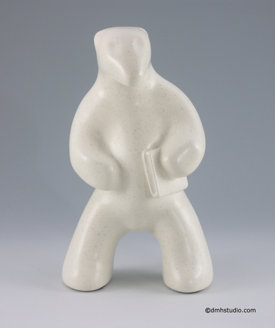 Large image of standing polar bear sculpture with book, in carrara white glaze. Portrait facing the viewer.