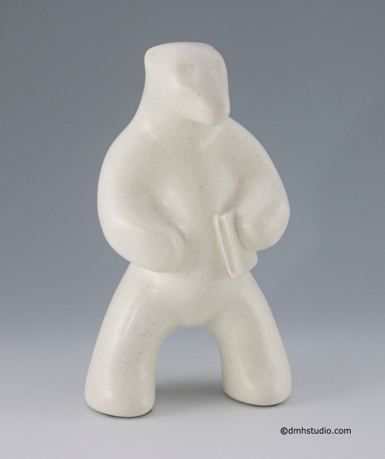 Large image of standing polar bear sculpture with book, in carrara white glaze. Portrait facing slightly to the viewers right.