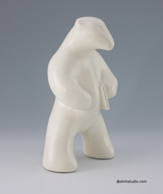Large image of standing polar bear sculpture with book, in carrara white glaze. Portrait facing to the viewers right.