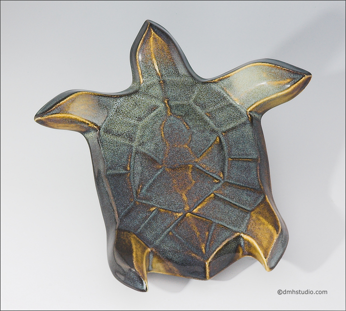 Large image of Flying Sea Turtle sculpture in gold and green glaze, seen  from above, facing top of the page.